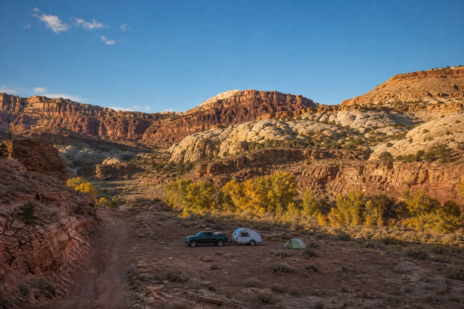 A truck, teardrop trailer, and tent in a red-rock Utah canyon